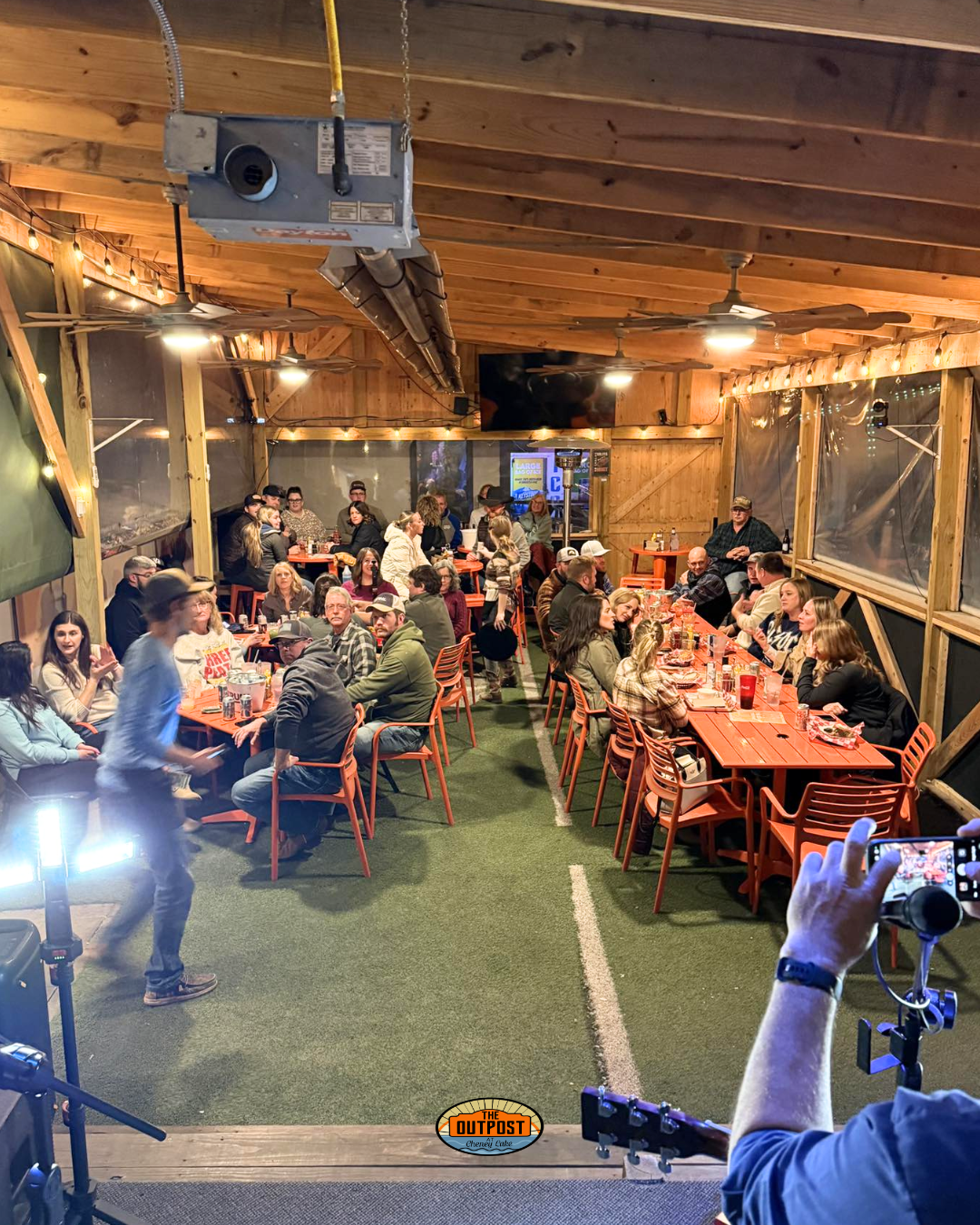 A packed beer garden at The Outpost watching a live acoustic performance