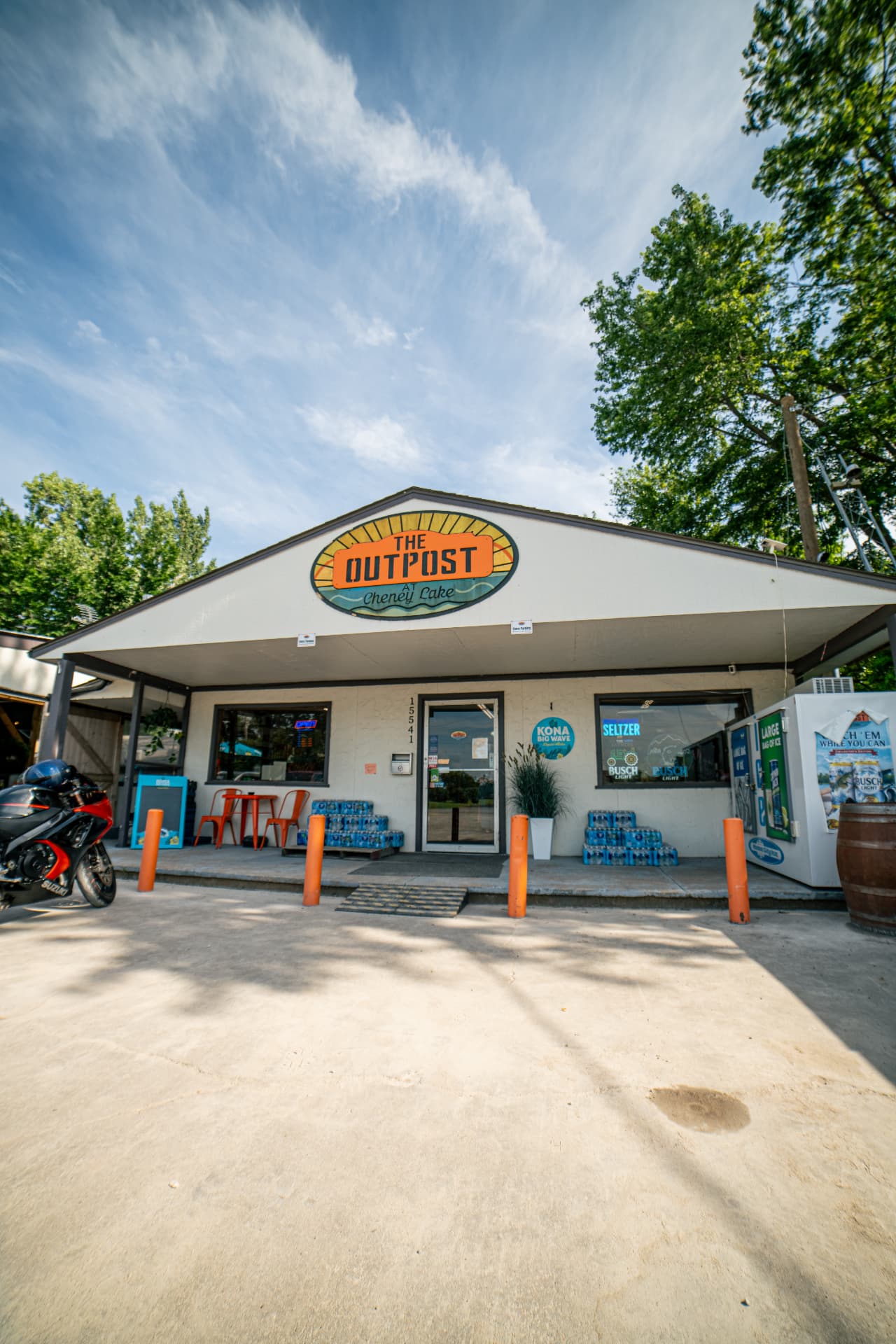 The Outpost storefront with orange bollards and the sign above the entrance