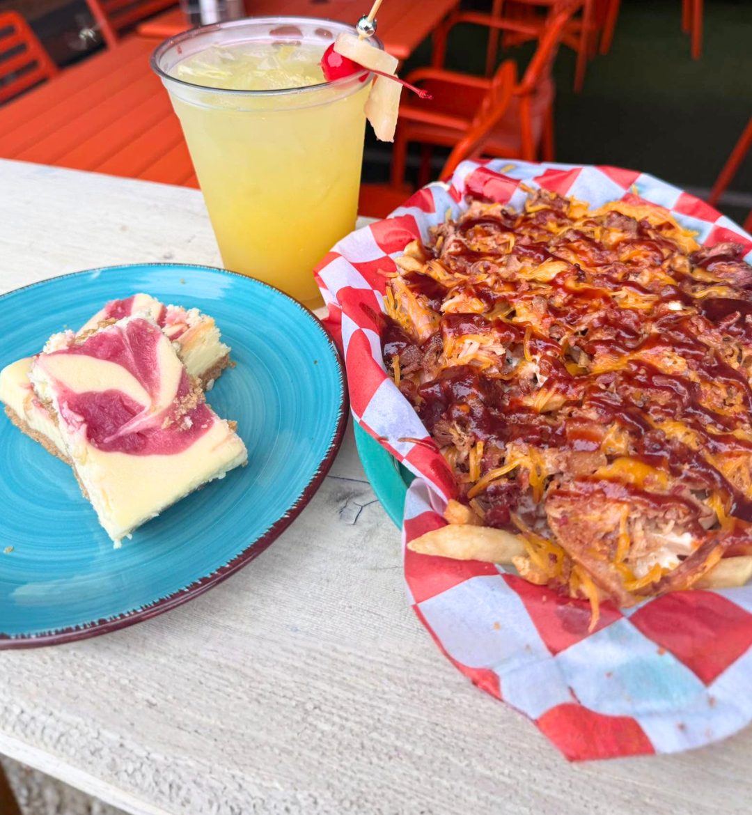 BBQ pulled pork loaded fries with a slice of raspberry swirl cheesecake and a cold cocktail