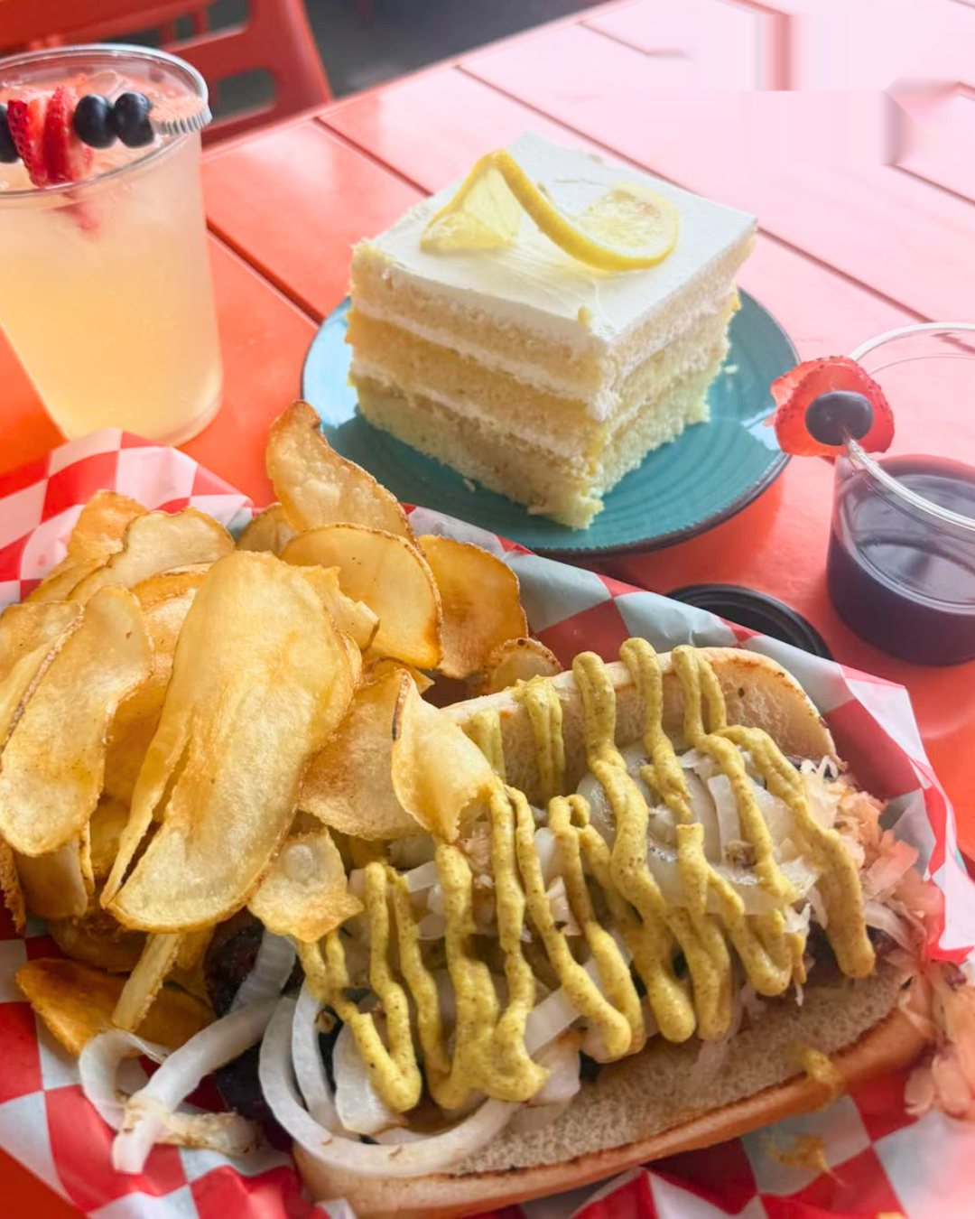 Loaded hot dog with sauerkraut, onions and mustard drizzle, house chips and a slice of lemon cake